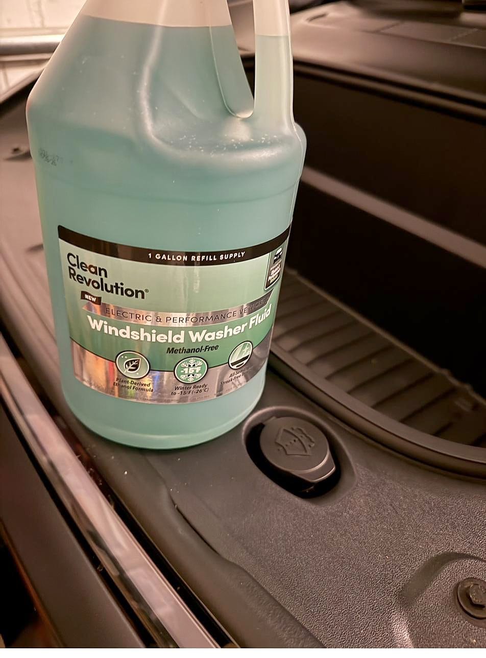 Gallon of washer fluid next to the washer reservoir filler cap in the Tesla Model Y front trunk