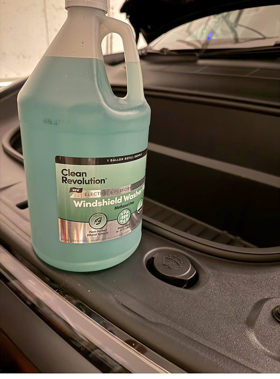 Gallon of Clean Revolution EV washer fluid sitting in the front trunk of a Tesla Model Y