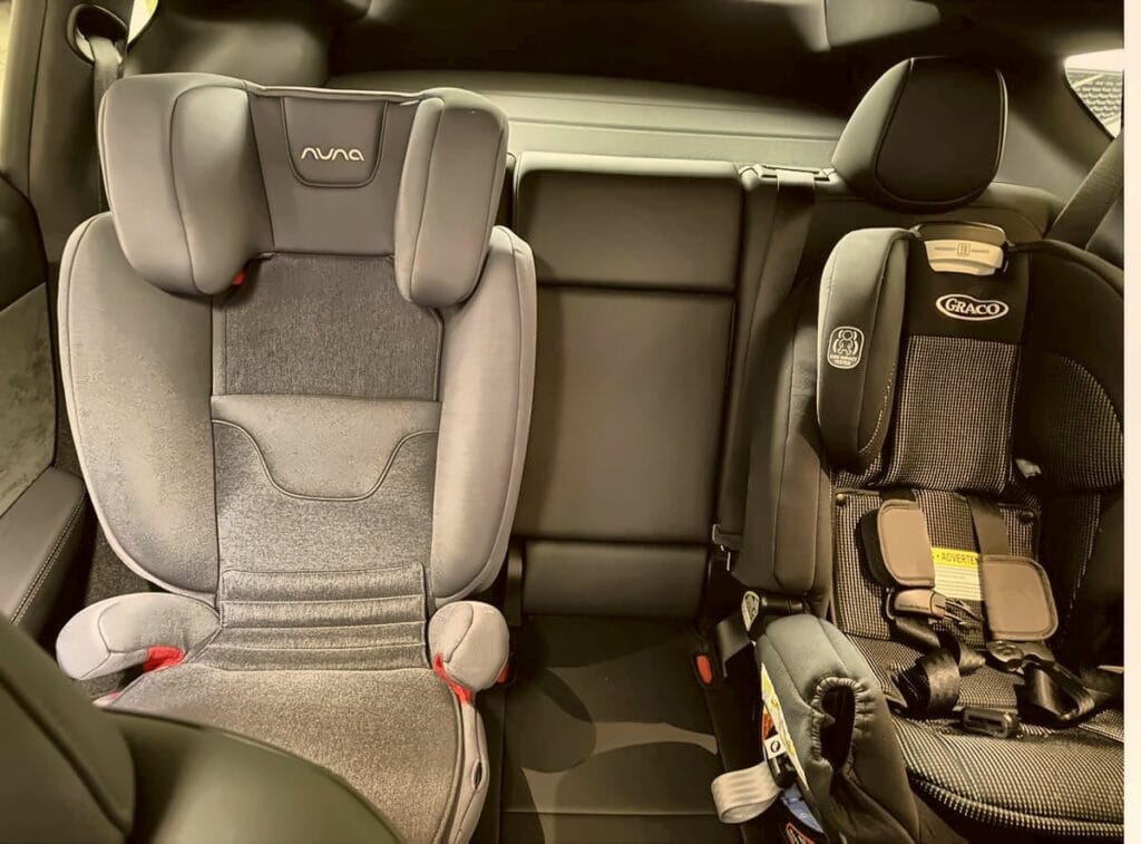 Nuna Aace booster next to a Graco 4Ever car seat in a Tesla Model Y