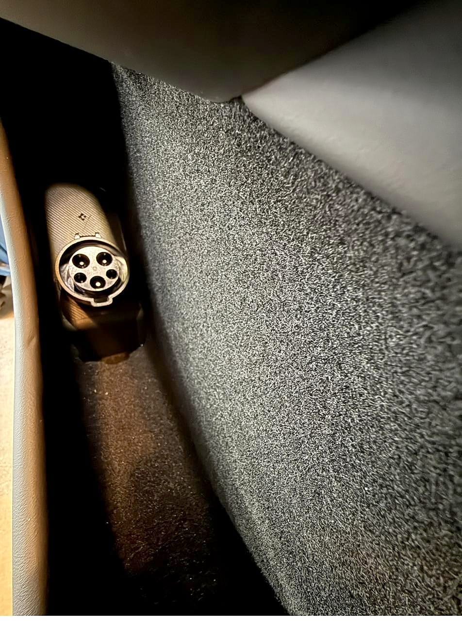Spigen J1772 adapter holder with the Tesla adapter docked, in the Tesla Model Y door pocket