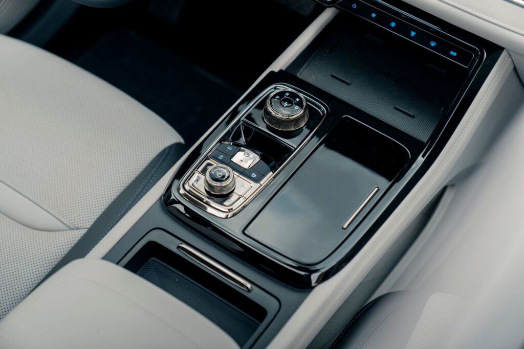 Close-up of a sleek modern car center console with controls and storage compartments