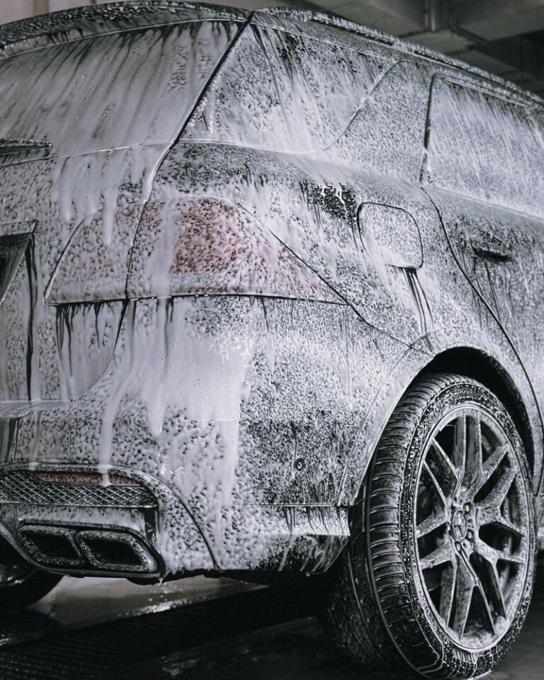 SUV covered in thick foam soap during a hand car wash, representative of Tesla Model Y detailing