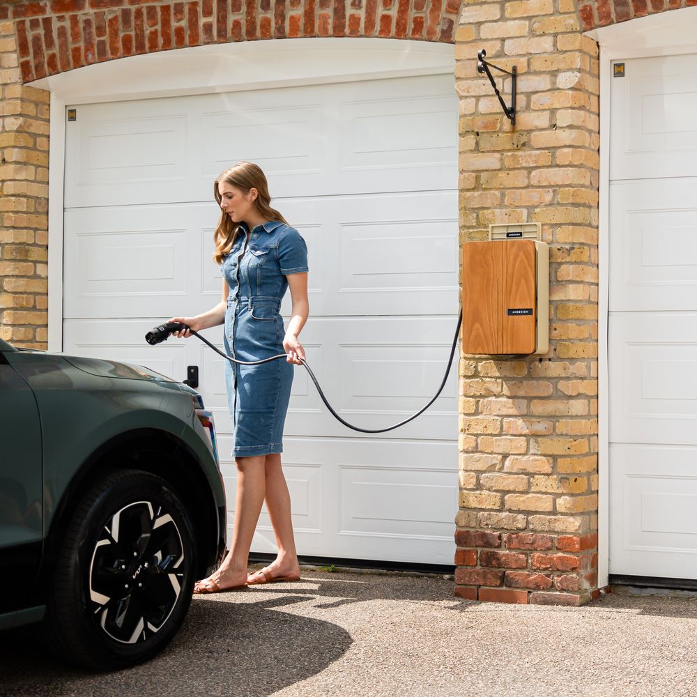 A woman connects her electric car to a home charging station in a residential garage