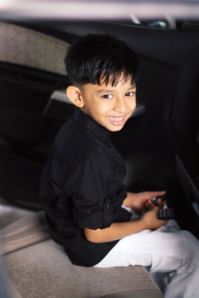 A smiling child seated comfortably in the backseat of a car