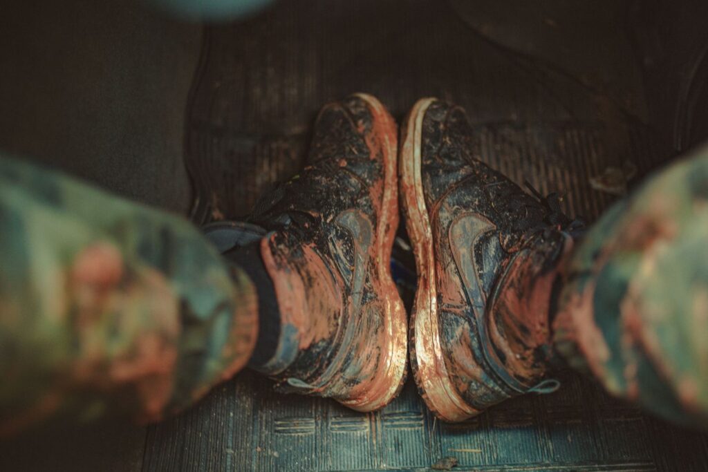 Overhead view of muddy sneakers on a car seat, illustrating the need for kick mats and seat protectors