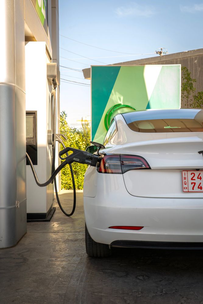Tesla electric vehicle charging at a station outdoors during the day
