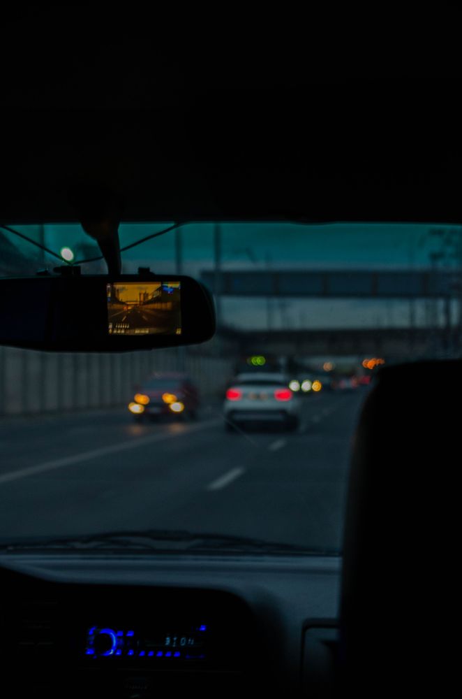 Dark highway seen through a car dashcam at night, representing Tesla Sentry Mode footage