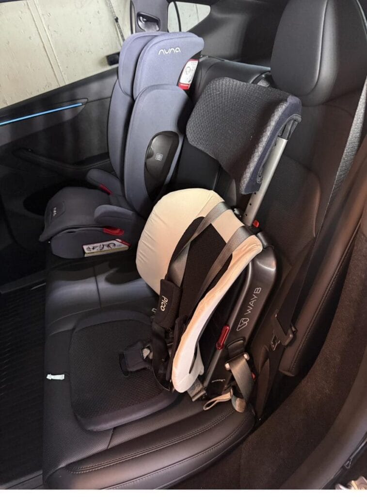 WAYB Pico next to a Nuna Aace booster in the back seat of a Tesla Model Y